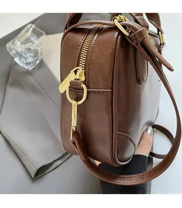 Detail of dark brown leather bag with high-quality gold hardware and precise stitching
