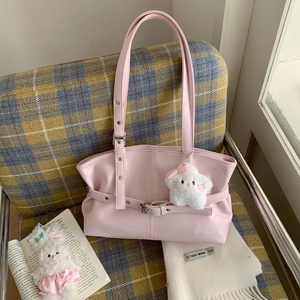 Detail of pink PU leather tote with adjustable strap and star plush on plaid chair