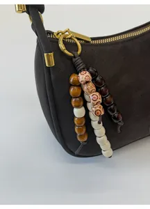 Vue détaillée du sac bandoulière en cuir marron foncé avec pompon en perles de bois