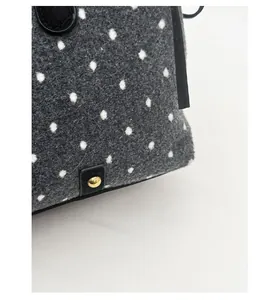 Detail of grey polka dot wool tote bag featuring gold hardware and black leather trim
