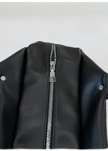 Detailed close-up of smooth silver metal zipper on textured black leather tote bag