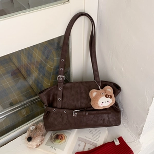 Close-up of vintage brown tote bag with silver buckles and a cute bear plush charm