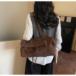 Dettaglio borsa tote in pelle scamosciata marrone con tracolle intrecciate e rivetti