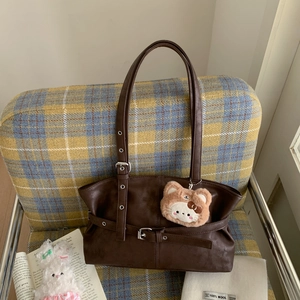 Detail of dark brown faux leather shoulder bag with buckle strap and plush charm