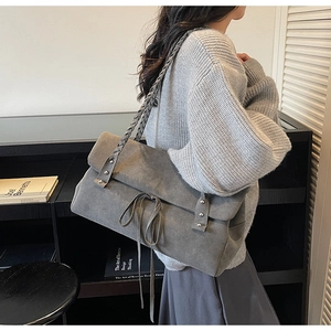 Detail of gray matte suede shoulder bag with braided strap and bow drawstring tie