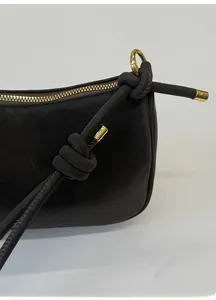 Détail de la bandoulière en cuir noué et des finitions dorées de ce sac à main marron