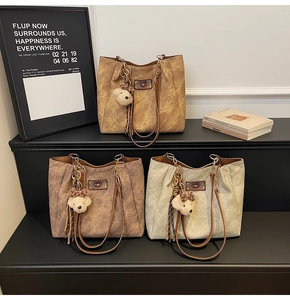 Detailed view of three textured leather tote bags in khaki, coffee, and off-white colors