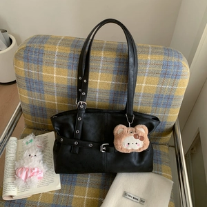 Detail of black faux leather tote bag with silver buckles and a brown plush bear charm