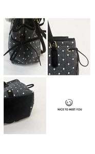 Detailed view of gray polka dot tote bag with side bow tie and metal zipper details