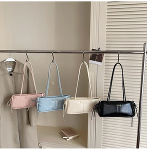 Detail view of four minimalist baguette bags in pastel colors hanging on a rack