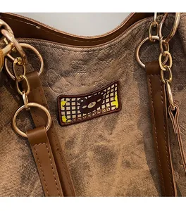 Close-up of brown textured tote bag with gold metal rings and bear embroidery