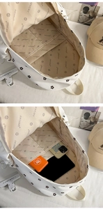 Detailed interior of a white floral canvas backpack with functional pockets and inner lining