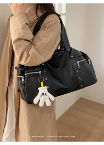 Detail of black PU leather motorcycle tote bag with silver studs and plush glove charm