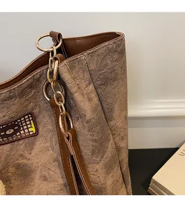 Close-up of brown tote bag showing gold chain strap and vintage textured fabric