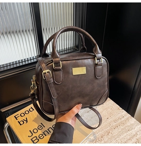 Detail of dark brown vintage faux leather handbag with golden hardware and adjustable strap