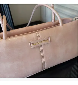 Detail of soft pink faux leather handbag with gold-stamped logo and matte texture