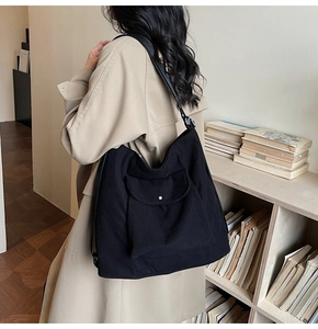 Detailed view of black corduroy tote bag texture and front pocket with metal button