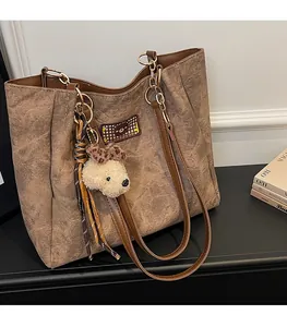 Detail of a brown tote bag featuring a cute bear patch and plush bear accessory