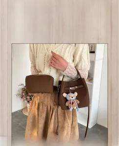 Detail of vintage brown bucket bag set with turn-lock closure and bear charm
