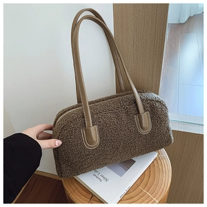 Detail of brown faux shearling tote bag with leather handles on a wooden stool
