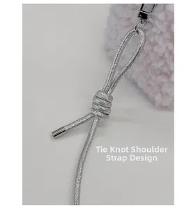 Detail of pink plush pillow bag featuring a silver woven cord strap with knot design