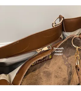Detail of smooth golden metal zipper and world map pattern on brown leather tote bag