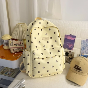 Detail of light yellow floral canvas backpack featuring a front pocket and side water bottle holder