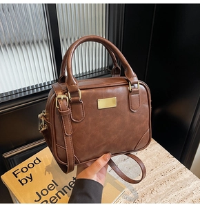 Detailed view of brown vintage satchel with pleated leather texture and gold hardware
