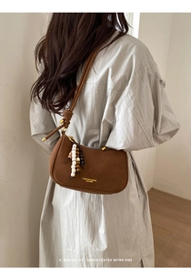 Gros plan d'un sac hobo en cuir marron rétro avec lettrage doré et perles en bois