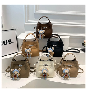 Litchi pattern bucket bags in multiple colors with cute teddy bear charms on white steps