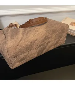Detailed view of the brown tote bag featuring textured 3D cartoon bear embossing