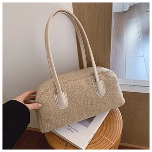 Detailed view of beige plush shoulder bag on wooden stool with soft ambient lighting