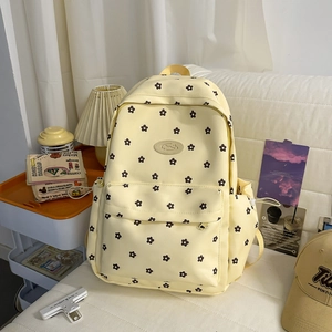 Detailed view of a yellow floral canvas backpack on a cozy sofa with home decor