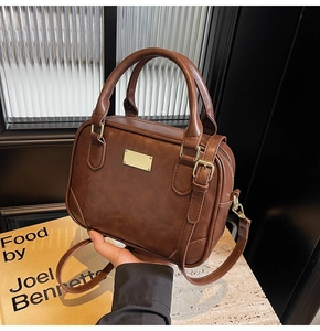 Detail of vintage brown leather Boston bag with gold metal plate and dual top handles