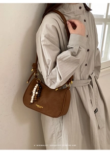 Détail du sac baguette marron vintage avec breloque à franges et bandoulière