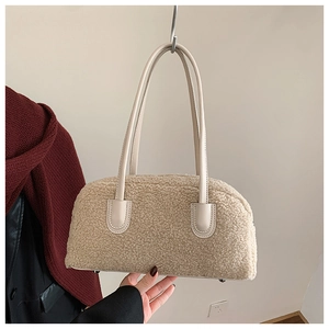 Detail of a creamy white fleece shoulder bag featuring smooth leather handles and metal feet