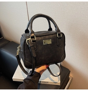 Detail of black faux leather bag with gold hardware and reinforced bottom edges
