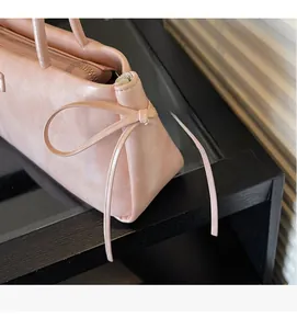 Close-up of the elegant leather bow detail and pearl finish texture on this pink shoulder bag