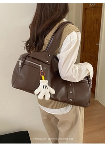 Detail of dark brown retro shoulder bag with functional zippers and cute glove charm