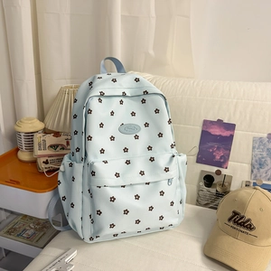 Close-up of light blue canvas backpack with brown floral patterns and zip front pocket