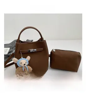 Detail of brown litchi leather bucket bag set with metal padlock and cute bear charm
