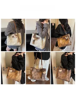 Detail view of vintage marble-textured tote bags in cream and coffee with bear charm