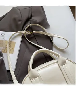 Détail du sac Boston en cuir blanc crème avec finitions dorées et bandoulière