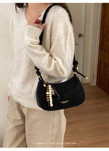 Détail du sac bandoulière demi-lune en cuir noir avec un pendentif en perles de bois unique