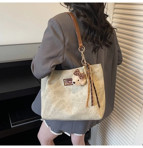Détail du cabas beige avec motifs d'ours gaufrés et breloque ours en peluche sur un modèle