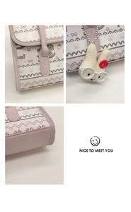 Detail of pink and white shoulder bag with strawberry prints and plush rabbit pendant
