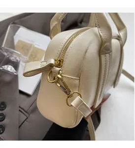 Gros plan sur un sac Boston crème avec texture litchi et détails en métal doré