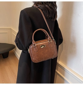 Brown vintage faux leather crossbody bag with gold buckle on a model in home setting