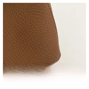 Macro view of brown lychee grain leather texture with precise stitching on a bucket bag