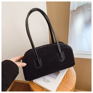 Close-up of black faux shearling shoulder bag with leather handles and metal zipper